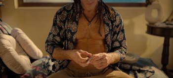 Movie still from “A Deadly Invitation” (2023), directed by J.M Cravioto – A man with a beard is using a cell phone; Medium shot, High angle