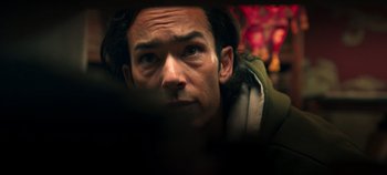 Movie still from “A Deadly Invitation” (2023), directed by J.M Cravioto – A man's face looking at the camera; Close Up shot, Low angle