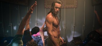 Movie still from “A Deadly Invitation” (2023), directed by J.M Cravioto – A man with long hair is standing in front of other people; Medium shot, Low angle