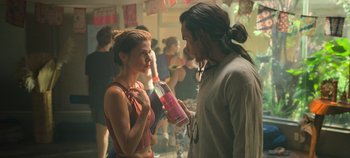 Movie still from “A Deadly Invitation” (2023), directed by J.M Cravioto – A man and a woman are standing in front of a crowd; Medium shot, Over the shoulder angle