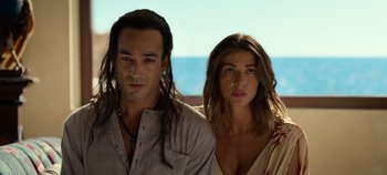 Movie still from “A Deadly Invitation” (2023), directed by J.M Cravioto – A man and a woman standing next to each other in front of a body of water; Close Up shot, Low angle