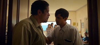 Movie still from “A Deadly Invitation” (2023), directed by J.M Cravioto – Two men standing next to each other in front of a crowd; Medium shot, Over the shoulder angle