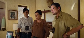 Movie still from “A Deadly Invitation” (2023), directed by J.M Cravioto – A group of people standing next to each other in a room; Medium shot, Over the shoulder angle