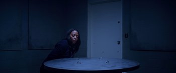Movie still from “A Fall from Grace” (2020), directed by Tyler Perry – A woman looking at a table in a dark room; Medium shot, High angle