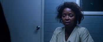 Movie still from “A Fall from Grace” (2020), directed by Tyler Perry – A woman sitting in front of a door in a room; Close Up shot, Over the shoulder angle