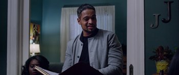 Movie still from “A Fall from Grace” (2020), directed by Tyler Perry – A man sitting in front of a book in front of a window; Close Up shot, Over the shoulder angle