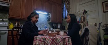 Movie still from “A Fall from Grace” (2020), directed by Tyler Perry – Two women sitting at a table in a kitchen; Medium shot, Over the shoulder angle