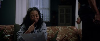 Movie still from “A Fall from Grace” (2020), directed by Tyler Perry – A woman sitting on a couch with a laptop in front of her face; Medium shot, High angle