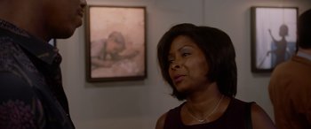Movie still from “A Fall from Grace” (2020), directed by Tyler Perry – A woman standing in front of a painting in a room; Medium shot, Over the shoulder angle