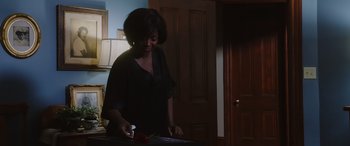 Movie still from “A Fall from Grace” (2020), directed by Tyler Perry – A woman standing in a dark room holding a knife and a rose; Medium shot, Over the shoulder angle