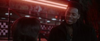 Movie still from “A Fall from Grace” (2020), directed by Tyler Perry – A man smiling at another man in front of neon lights; Close Up shot, Over the shoulder angle
