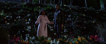 Movie still from “A Fall from Grace” (2020), directed by Tyler Perry – A man and a woman holding hands in front of a forest at night; Wide shot, Low angle