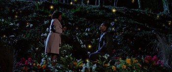 Movie still from “A Fall from Grace” (2020), directed by Tyler Perry – A man and a woman are sitting in a field of fireflies at night; Extreme Wide shot, High angle