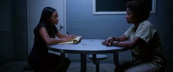 Movie still from “A Fall from Grace” (2020), directed by Tyler Perry – Two people sitting at a round table in a room; Medium shot, Over the shoulder angle