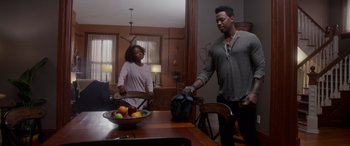 Movie still from “A Fall from Grace” (2020), directed by Tyler Perry – A man and a woman standing in front of a bowl of fruit on a table; Wide shot, Over the shoulder angle