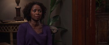 Movie still from “A Fall from Grace” (2020), directed by Tyler Perry – A woman in a purple shirt sitting in front of a green plant; Close Up shot, Over the shoulder angle