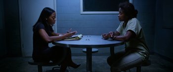 Movie still from “A Fall from Grace” (2020), directed by Tyler Perry – Two people sitting at a table in front of each other; Wide shot, High angle