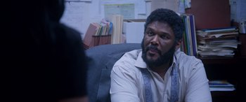 Movie still from “A Fall from Grace” (2020), directed by Tyler Perry – A man sitting in a chair in front of papers; Close Up shot, Over the shoulder angle