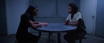 Movie still from “A Fall from Grace” (2020), directed by Tyler Perry – Two women sitting at a round table talking to each other; Medium shot, High angle