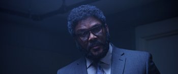 Movie still from “A Fall from Grace” (2020), directed by Tyler Perry – A man in a suit and tie wearing glasses; Close Up shot, Low angle