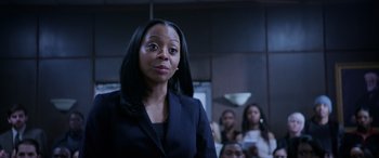 Movie still from “A Fall from Grace” (2020), directed by Tyler Perry – A woman standing in front of a group of people; Close Up shot, Over the shoulder angle
