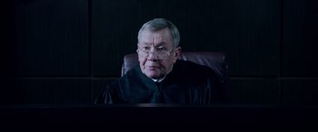 Movie still from “A Fall from Grace” (2020), directed by Tyler Perry – An older man wearing a black robe and glasses; Close Up shot, Over the shoulder angle