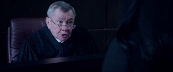 Movie still from “A Fall from Grace” (2020), directed by Tyler Perry – An older man wearing a black robe and glasses; Close Up shot, Over the shoulder angle