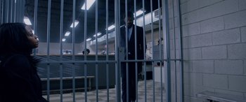 Movie still from “A Fall from Grace” (2020), directed by Tyler Perry – A man in a suit standing behind a metal gate; Wide shot, High angle
