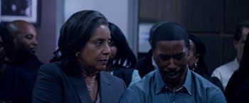Movie still from “A Fall from Grace” (2020), directed by Tyler Perry – A woman standing next to a man in front of a group of people; Close Up shot, Over the shoulder angle