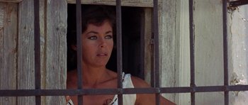 Movie still from “A Fistful of Dollars” (1964), directed by Sergio Leone – A woman looking out a window through a metal fence; Close Up shot, Low angle
