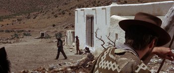 Movie still from “A Fistful of Dollars” (1964), directed by Sergio Leone – A couple of men standing in front of a building; Wide shot, Over the shoulder angle