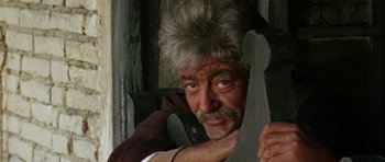 Movie still from “A Fistful of Dollars” (1964), directed by Sergio Leone – An older man with a beard and mustache holding a pair of scissors; Close Up shot, Low angle