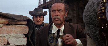 Movie still from “A Fistful of Dollars” (1964), directed by Sergio Leone – A man in a suit and tie holding a gun; Close Up shot, Low angle
