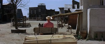 Movie still from “A Fistful of Dollars” (1964), directed by Sergio Leone – A man sitting in a carriage in a village; Wide shot, Over the shoulder angle