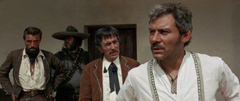 Movie still from “A Fistful of Dollars” (1964), directed by Sergio Leone – A group of men standing next to each other in a room; Medium shot, Low angle