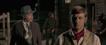 Movie still from “A Fistful of Dollars” (1964), directed by Sergio Leone – A group of men standing next to each other on a street; Medium shot, Over the shoulder angle