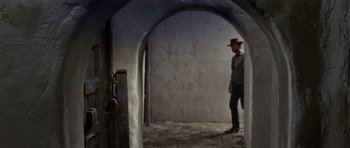 Movie still from “A Fistful of Dollars” (1964), directed by Sergio Leone – A man wearing a hat standing in an archway; Wide shot, Low angle