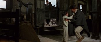 Movie still from “A Fistful of Dollars” (1964), directed by Sergio Leone – A man and a child in front of an open door; Wide shot, Over the shoulder angle