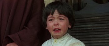 Movie still from “A Fistful of Dollars” (1964), directed by Sergio Leone – A young boy crying with his eyes closed; Close Up shot, High angle