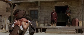Movie still from “A Fistful of Dollars” (1964), directed by Sergio Leone – A man standing on the steps of an old house; Wide shot, Over the shoulder angle