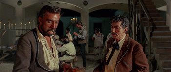 Movie still from “A Fistful of Dollars” (1964), directed by Sergio Leone – A group of people in a room with a painting on the wall; Medium shot, Low angle