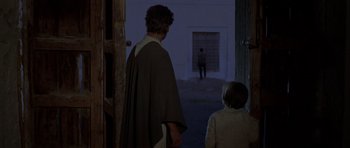 Movie still from “A Fistful of Dollars” (1964), directed by Sergio Leone – A man and a boy are standing in a doorway; Wide shot, Over the shoulder angle