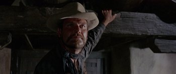Movie still from “A Fistful of Dollars” (1964), directed by Sergio Leone – A man in a cowboy hat pointing to the ceiling; Close Up shot, Low angle