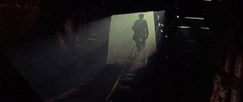 Movie still from “A Fistful of Dollars” (1964), directed by Sergio Leone – A man walking down a train track in the dark; Wide shot, Low angle