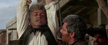 Movie still from “A Fistful of Dollars” (1964), directed by Sergio Leone – A man is hanging from a rope by a rope and another man is hanging from a rope; Close Up shot, Low angle