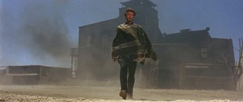 Movie still from “A Fistful of Dollars” (1964), directed by Sergio Leone – A man walking in the dirt with a blanket over his head; Wide shot, Low angle