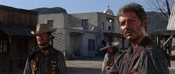 Movie still from “A Fistful of Dollars” (1964), directed by Sergio Leone – A man in a cowboy hat standing in front of a building; Medium shot, Low angle
