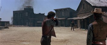 Movie still from “A Fistful of Dollars” (1964), directed by Sergio Leone – A man is shooting a gun in the middle of the desert; Wide shot, Over the shoulder angle
