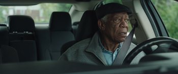 Movie still from “A Good Person” (2023), directed by Zach Braff – An older man sitting in the back seat of a car; Close Up shot, Over the shoulder angle