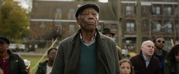 Movie still from “A Good Person” (2023), directed by Zach Braff – An older man in a hat and a jacket; Close Up shot, Low angle